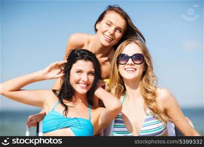 summer holidays and vacation - girls in bikinis sunbathing on the beach chairs