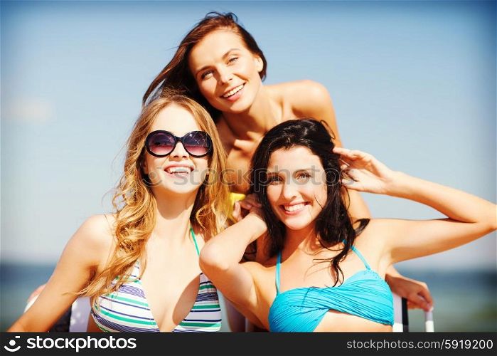 summer holidays and vacation - girls in bikinis sunbathing on the beach chairs. girls sunbathing on the beach chairs