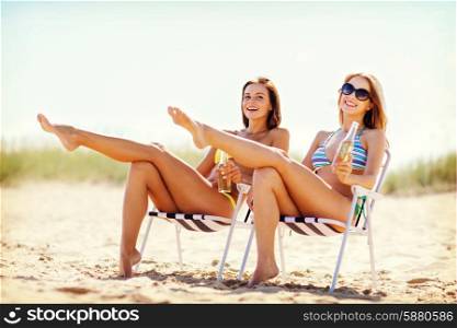 summer holidays and vacation - girls in bikinis with drinks on the beach chairs