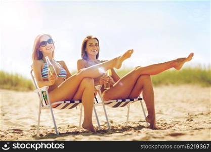 summer holidays and vacation - girls in bikinis with drinks on the beach chairs. girls with drinks on the beach chairs