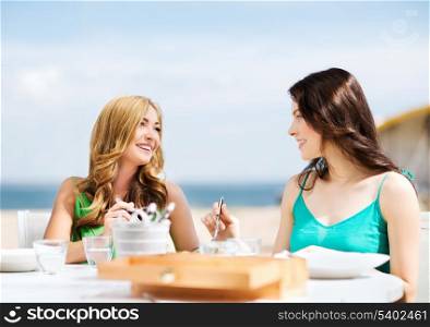 summer holidays and vacation - girls in cafe on the beach