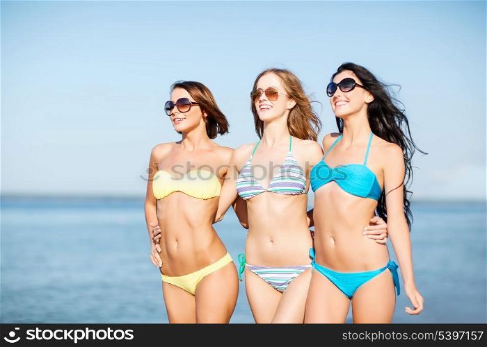 summer holidays and vacation - girls in shades and bikini walking on the beach
