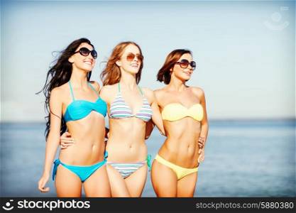 summer holidays and vacation - girls in shades and bikini walking on the beach