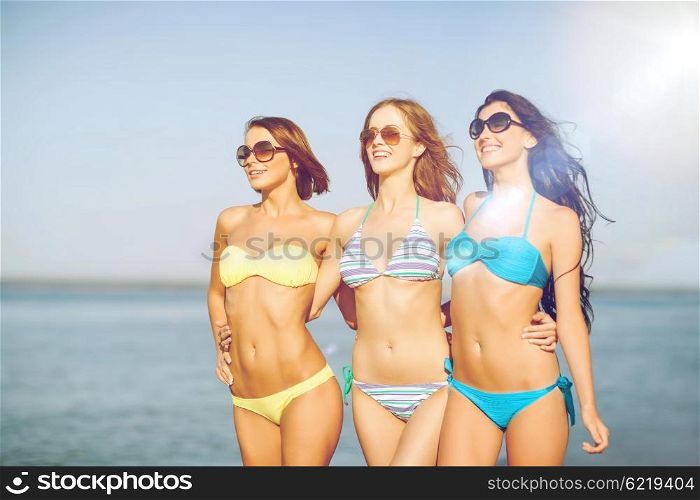 summer holidays and vacation - girls in shades and bikini walking on the beach. girls in bikini walking on the beach