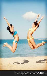summer holidays and vacation - girls jumping on the beach