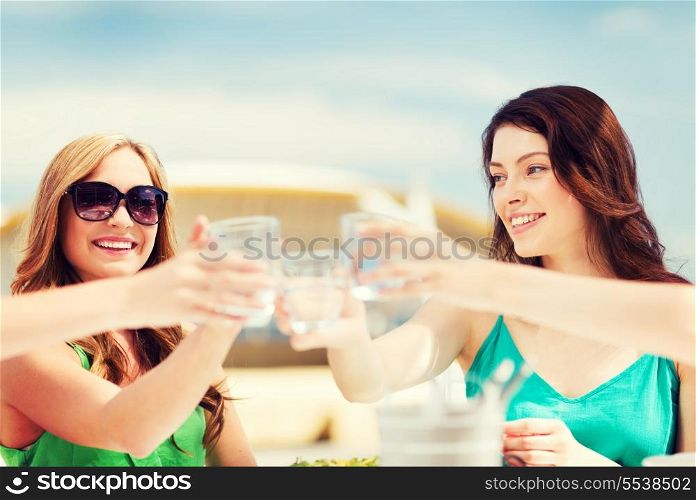summer holidays and vacation - girls making a toast in cafe on the beach