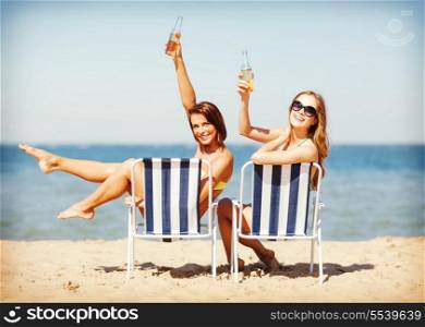 summer holidays and vacation - girls sunbathing and drinking on the beach chairs