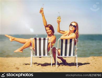 summer holidays and vacation - girls sunbathing and drinking on the beach chairs. girls sunbathing on the beach chairs