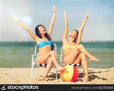 summer holidays and vacation - girls sunbathing on the beach chairs. girls sunbathing on the beach chairs