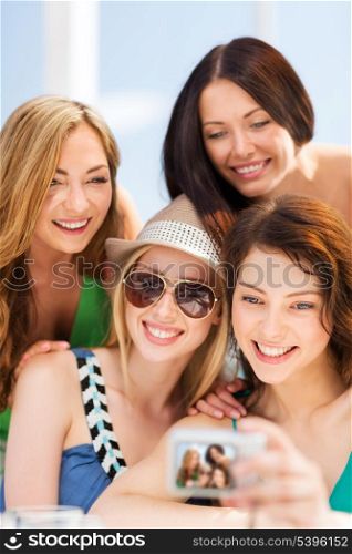 summer holidays and vacation - girls taking photo in cafe on the beach