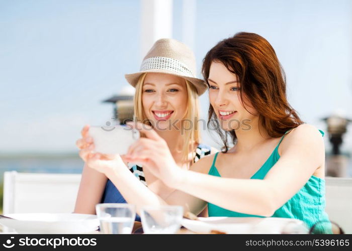 summer holidays and vacation - girls taking photo in cafe on the beach