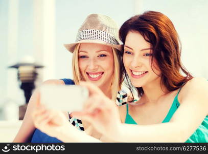 summer holidays and vacation - girls taking photo in cafe on the beach