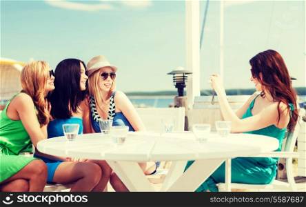 summer holidays and vacation - girls taking photo with digital camera in cafe on the beach