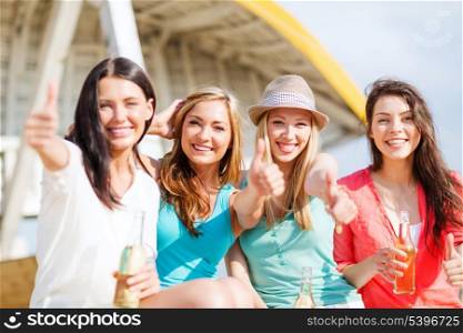 summer holidays and vacation - girls with drinks showing thumbs up on the beach