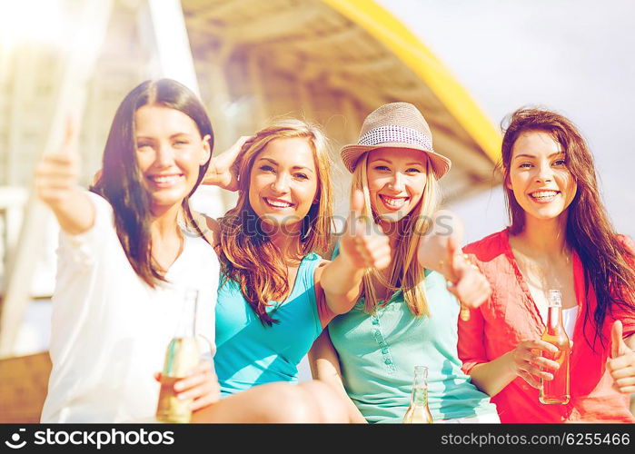 summer holidays and vacation - girls with drinks showing thumbs up on the beach. girls with drinks on the beach