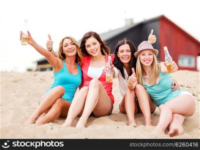 summer holidays and vacation - girls with drinks showing thumbs up on the beach. girls with drinks on the beach