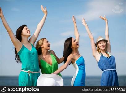 summer holidays and vacation - girls with hands up on the beach. girls looking at the sea with hands up