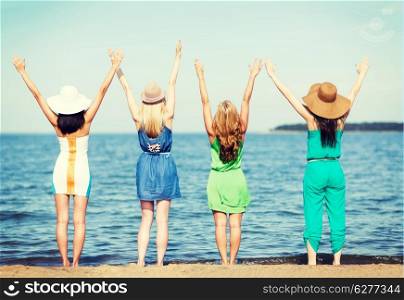summer holidays and vacation - girls with hands up on the beach