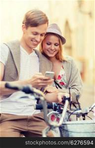 summer holidays, apps and dating concept - couple with bicycles and smartphone in the city