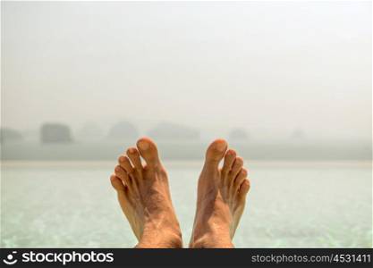 summer holidays, beach, travel, leisure and body care concept - closeup of male feet over sea and sky