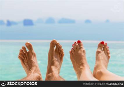 summer holidays, beach, travel, leisure and body care concept - closeup of couple feet over sea and sky on beach