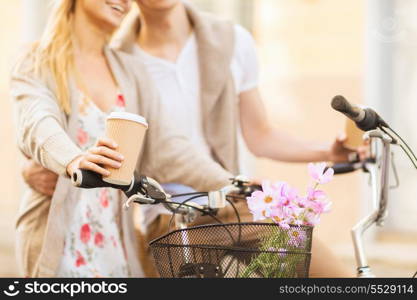 summer holidays, bikes, love, relationship and dating concept - closeup of couple holding coffee and riding bicycle