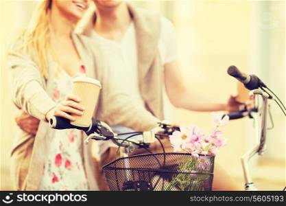 summer holidays, bikes, love, relationship and dating concept - closeup of couple holding coffee and riding bicycle
