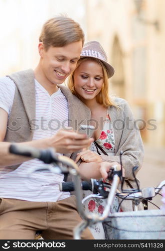 summer holidays, bikes, love, relationship, navigation, gps and dating concept - couple with bicycles and smartphone in the city