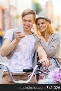 summer holidays, bikes, love, relationship, navigation, gps and dating concept - couple with bicycles and smartphone in the city