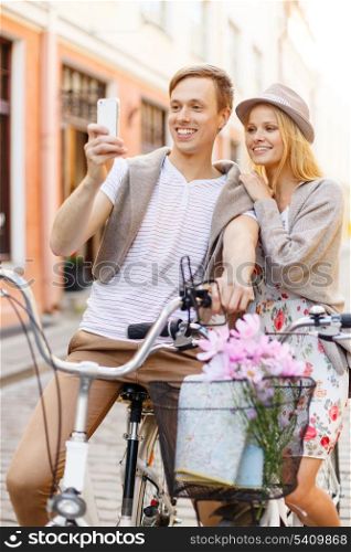 summer holidays, bikes, love, relationship, navigation, gps and dating concept - smiling couple with bicycles and smartphone in the city