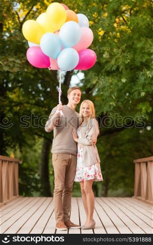 summer holidays, celebration and dating concept - couple with colorful balloons in the park