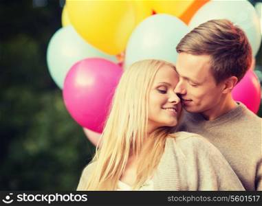 summer holidays, celebration and dating concept - couple with colorful balloons kissing in the park