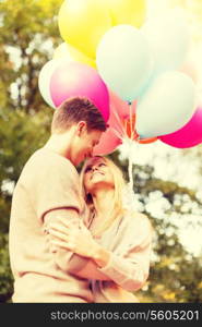 summer holidays, celebration and dating concept - smiling couple with colorful balloons in the park