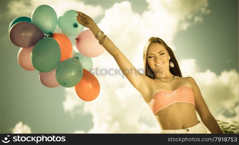 Summer holidays, celebration and lifestyle concept - attractive woman teen girl with colorful balloons outside on beach blue sky background. Aged tone