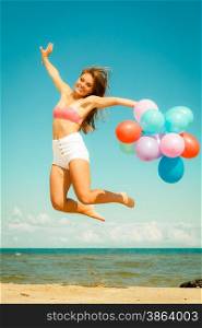 Summer holidays, celebration and lifestyle concept - beautiful woman teen girl jumping with colorful balloons outside on beach