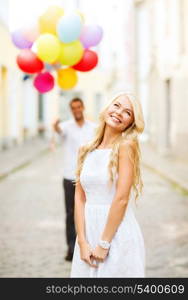 summer holidays, celebration and relationships concept - woman and man with colorful balloons in the city