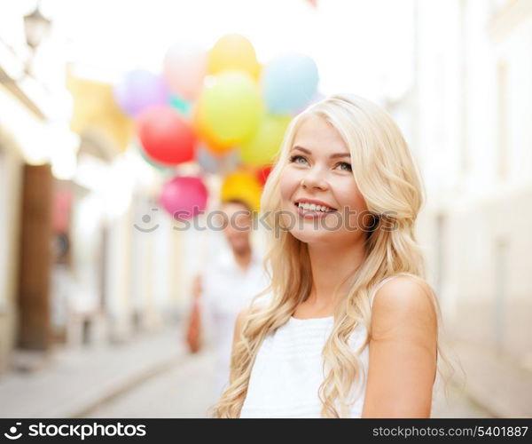 summer holidays, celebration and relationships concept - woman and man with colorful balloons in the city