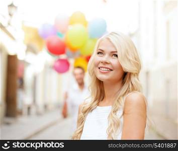 summer holidays, celebration and relationships concept - woman and man with colorful balloons in the city