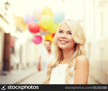 summer holidays, celebration and relationships concept - woman and man with colorful balloons in the city