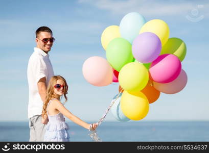 summer holidays, celebration, children and family concept - happy father and daughter with colorful balloons at seaside