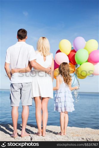 summer holidays, celebration, children and people concept - happy family at the seaside with bunch of colorful balloons