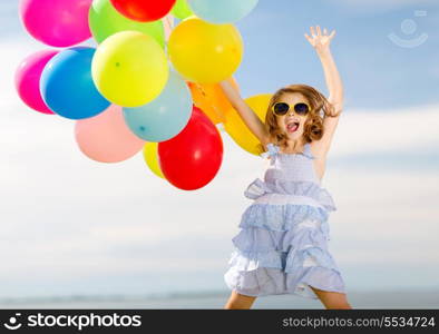 summer holidays, celebration, children and people concept - happy jumping girl with colorful balloons outdoors