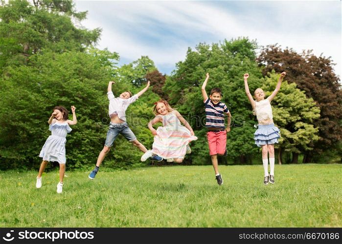 summer holidays, childhood and frinedship concept - happy kids having fun and jumping in park. happy kids jumping in summer park. happy kids jumping in summer park