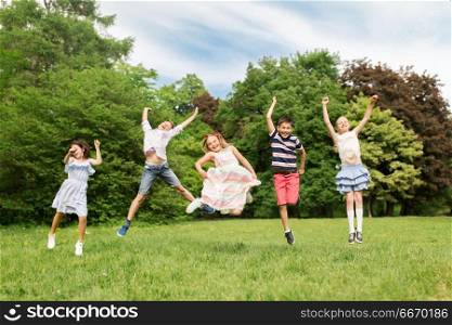 summer holidays, childhood and frinedship concept - happy kids having fun and jumping in park. happy kids jumping in summer park. happy kids jumping in summer park