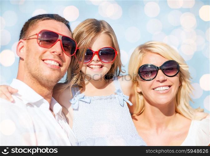 summer holidays, children and people concept - happy family in sunglasses over blue lights background