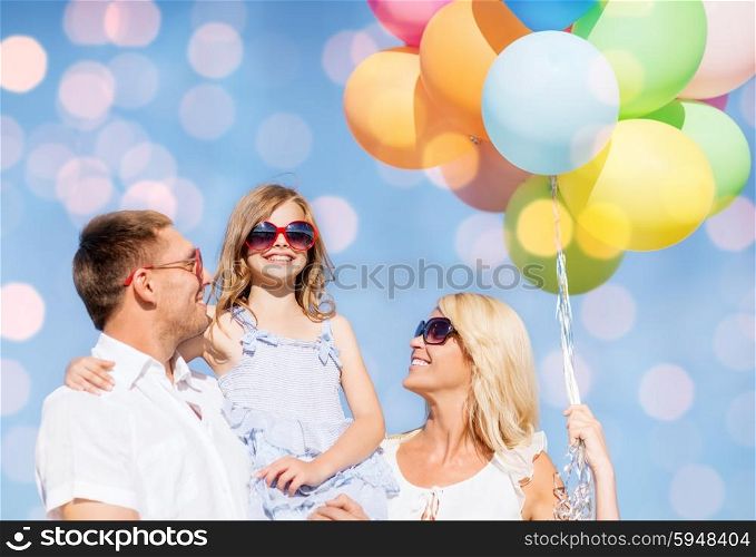 summer holidays, children and people concept - happy family in sunglasses with air balloons over blue lights background