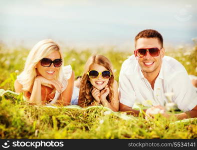 summer holidays, children and people concept - happy family with blue sky and green grass