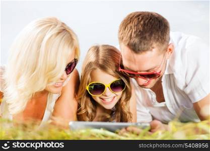 summer holidays, children and people concept - happy family with tablet pc, blue sky and green grass taking picture