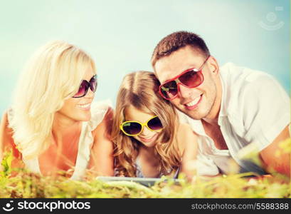 summer holidays, children and people concept - happy family with tablet pc, blue sky and green grass