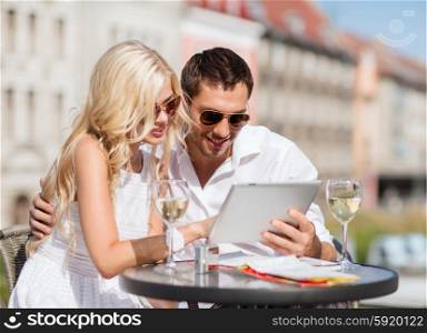 summer holidays, dating and technology concept - couple looking at tablet pc in cafe in the city